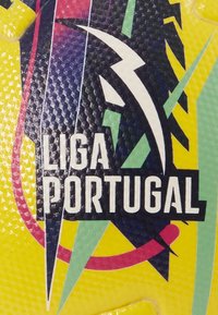 Pallone da calcio giallo con una superficie texture, lettere nere in grassetto "LIGA PORTUGAL" e accenti geometrici colorati in verde e rosa.