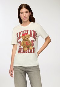 Biała koszulka z grafiką przedstawiającą misia w czerwonej czapce z napisem "Love" oraz wyraźnym czerwonym nadrukiem "Cleveland" i "Ohio State".