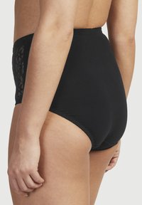 Högmidjade svarta trosor tillverkade i slät tyg med spetsdetaljer på sidorna. Har elastisk midjeband och sömdetaljer.