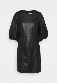 Robe noire en simili cuir avec manches courtes bouffantes et col rond, fermeture éclair au dos.