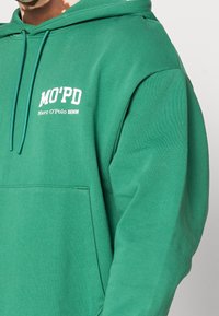 Sudadera verde de mezcla de algodón, con un bolsillo frontal, capucha ajustable con cordón y logo impreso en blanco en el pecho.