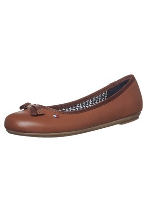 Chaussure ballerine plate en cuir marron avec un petit nœud sur le devant et une doublure intérieure à motif, avec un petit logo drapeau rectangulaire sur le côté.