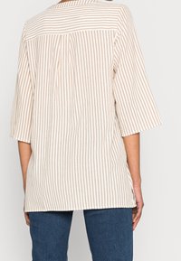 Leichtes, beige- und cremefarben gestreiftes Oberteil mit kurzen Ärmeln, Rückendetail mit Faltendetail und relaxed Fit, aus weicher Stoffqualität.