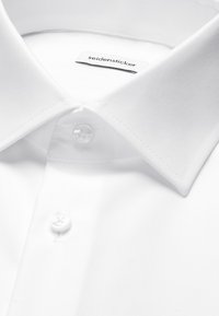 Weißes Hemd mit spitzem Kragen, zwei geknöpften Knöpfen und sichtbarem „seidensticker“-Markenlabel im Kragen.