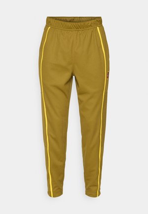 Pantalones de chándal verde oliva con rayas laterales amarillas, cintura elástica, piernas ajustadas y un pequeño parche con logo en la parte superior izquierda.