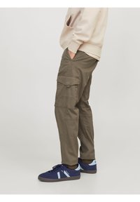 Pantalones cargo verde oliva con bolsillos laterales, de corte holgado y dobladillos enrollados, combinados con zapatillas navy con detalles en azul claro.
