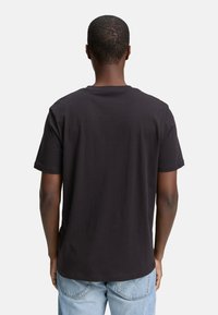 Schwarzes Baumwoll-T-Shirt mit kurzen Ärmeln, einem Rundhalsausschnitt und einem lässigen Schnitt, von hinten gegen einen schlichten weißen Hintergrund gezeigt.