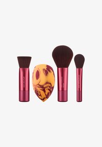 Set med fyra sminkverktyg: tre borstar med röda handtag och mjuka, mörka borst, plus en svamp i orange och gul med marmorerad design.
