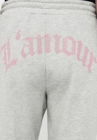 Ανοιχτό γκρι φόρμες με ροζ γοτθικό κείμενο που γράφει "L'amour" στη μέση πίσω μέρος.