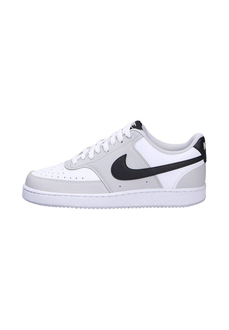 White leather sneakers with grey accents, black logo, perforated toe, and white rubber sole. Rounded shape and lace-up closure.