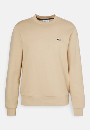 Beige sweatshirt gemaakt van zacht materiaal, met een ronde halslijn en geribde mouwen. Klein geborduurd logo op het linker borstgedeelte.