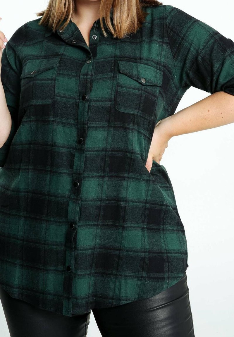 Koszula w zielono-czarną kratę na guziki, z dwoma kieszeniami na piersi, długim rękawem i luźnym krojem. Wykonana z miękkiej tkaniny o gładkiej fakturze.