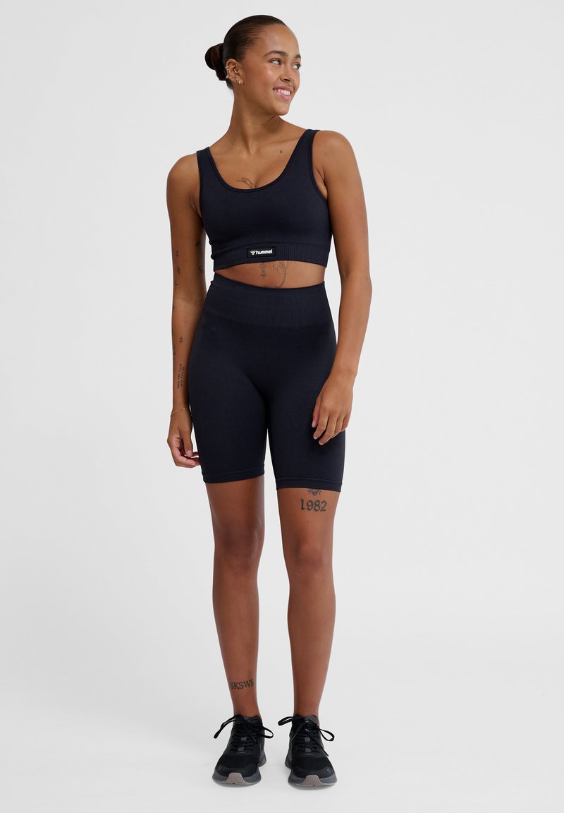 Zwarte sportbeha en bijpassende hoge shorts, gemaakt van soepel, rekbaar materiaal. Heeft een logo-tag op de band van de beha.
