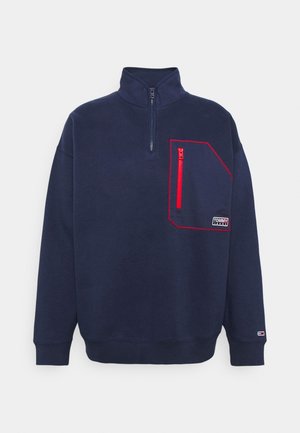 Navy blue sweatshirt with a high collar, half-zip front, and a red zippered pocket on the left chest. Features ribbed cuffs and hem.