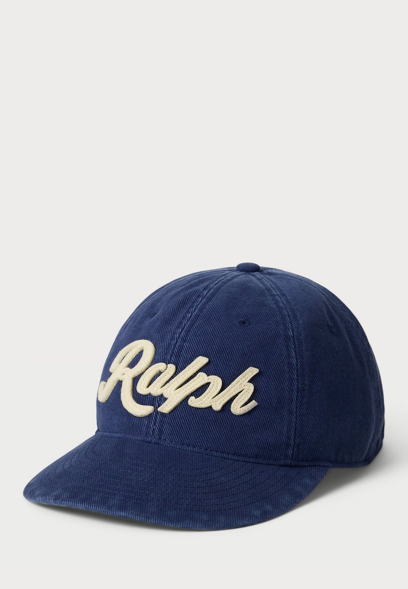 Casquette en velours côtelé bleu marine avec une visière incurvée, ornée de "Ralph" brodé en fil de couleur crème sur le devant. Surface en tissu texturée.
