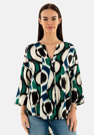 Blouse multicolore en tissu avec de grands motifs noirs, verts et bleus ; présente un décolleté en V et des manches trois-quarts.