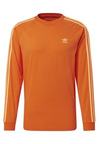 Camiseta de algodón naranja de manga larga con tres rayas blancas en cada hombro y un pequeño logo blanco en el pecho.