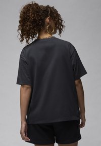 Black cotton t-shirt with short sleeves, relaxed fit, and a round neckline, paired with black shorts. Simple, solid design and smooth texture.