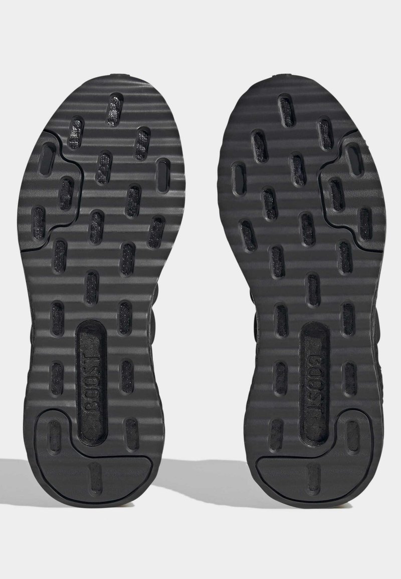 Schwarze Schuhsohlen mit strukturierten rechteckigen Profilen und geripptem Muster, die in der Mitte jeder Sohle mit "BOOST" beschriftet sind.