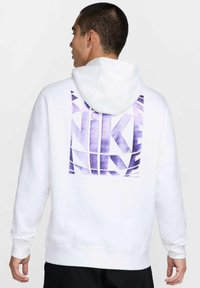 Sudadera con capucha blanca hecha de tela suave, con un gran logo morado de Nike y un diseño geométrico en la espalda. Estilo tipo pulóver con capucha.
