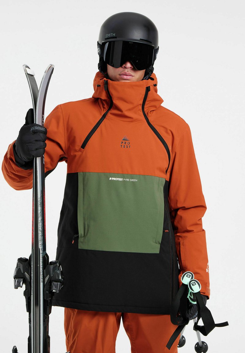 Orangen- und schwarze, wasserdichte Skijacke mit grünen Akzenten, Reißverschluss-Tasche und verstellbarem Kapuze. Glänzender schwarzer Helm und Skistöcke.