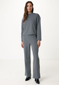 Tryckt loungeklädesset med en höghalsskurtaj och utsvängda byxor i marinblå och vit mönster. Slät tyg med avslappnad passform.