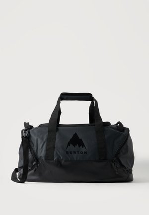 Bolsa de viaje negra Burton con dos asas, correa de hombro y logo de montaña en el frente sobre un fondo blanco.