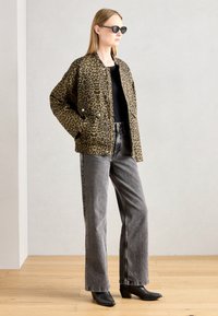 Lepardprintet jakke i brun og sort stoff, parret med høytlivede grå jeans og svarte spisse støvler.