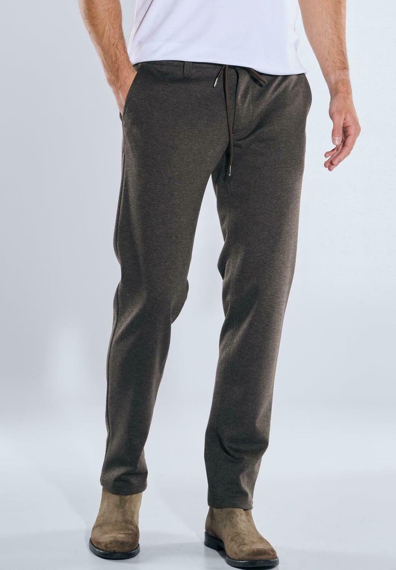 Brown athletic pants with an elastic waistband and drawstring. Made of textured fabric, featuring side pockets and a tapered fit.
