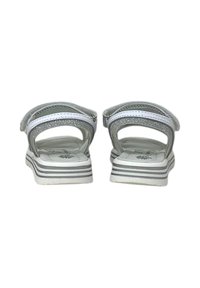 Sandali bianchi con suola testurizzata, cinturini argentati glitterati e strisce grigie sulla suola. La vista posteriore evidenzia le chiusure regolabili.