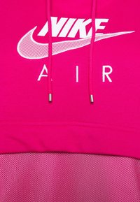 Nike Air sweatshirt i ljusrosa med en texturerad mesh-nederkant, med en vit logotyp och bokstäver på den övre delen.