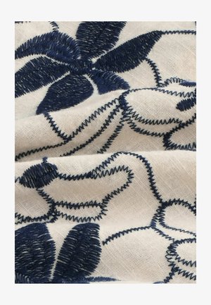 Embroidered fabric featuring navy blue floral patterns on a natural-colored linen background, with textured stitching and smooth folds.