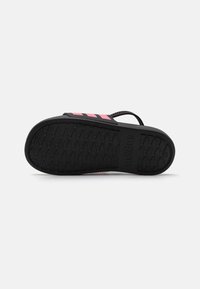 Soletta nera in gomma con marchio adidas rosa. Il motivo in gomma testurizzata offre grip. La parte superiore in tessuto sintetico liscio presenta cinghie regolabili.