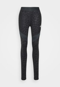 Leggins neri stampati con motivo leopardato, realizzati in tessuto elasticizzato, con un'ampia vita e accenti neri angolati sulle cosce.