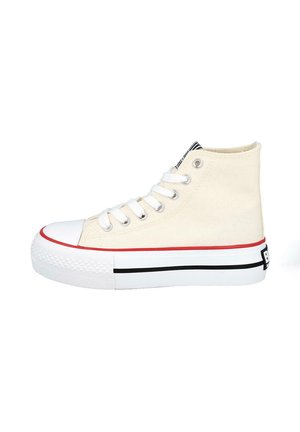 Zapatilla de lona beige de caña alta con cordones blancos, suela de goma blanca, rayas rojas y negras, y puntera reforzada.