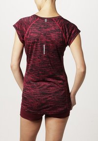 Camisa atlética de rayas rojas y negras con mangas cortas y diseño raglán, que presenta un detalle reflectante en la parte posterior y una textura suave.