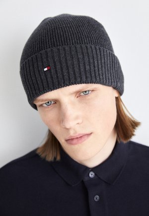 Gorro de punto acanalado en gris oscuro con un pequeño logo en rojo, blanco y azul en la parte frontal, hecho de un material suave y cálido.