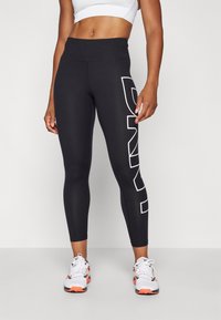 Black leggings with a high waist, featuring a bold white logo on the left side. Made of stretchy material, designed for comfort and performance.