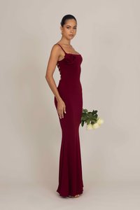 Burgundy-housuja, jossa on spagettiolkaimet, ruusukuvio rinnan kohdalla ja sivuleikkaukset. Sileä kangas, lattiaa hipova malli ja pehmeä laskos.