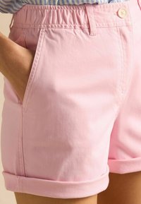 Svetloružové šortky s elastickým pásom, so stranovými vreckami a zavinutými lemami. Vyrobené z hladkej, priedušnej látky pre pohodlie.