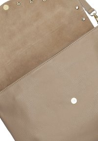Beige leren handtas met een zachte, textuurafwerking. Beschikt over een gladde, tan binnenkant en zilveren hardware accenten langs de bovenrand.