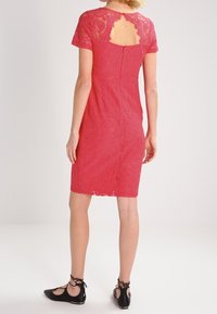 Červené krajkové šaty s přiléhavým střihem, krátkými rukávy a detailem ve tvaru klíčové dírky na zádech. Krátká délka s propracovanými květinovými vzory.