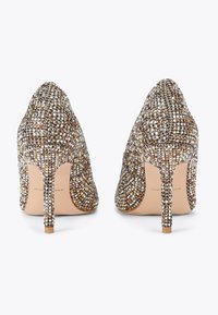 Scarpe con tacco alto, rivestite in un tessuto di paillettes multicolori, con punta affusolata e sottile tacco a stiletto. Suola di un beige chiaro.