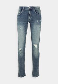 Vaqueros ajustados de denim desgastado, con un color azul desvanecido, rotos en las rodillas, cinco bolsillos y una cinturilla con cierre de botón.
