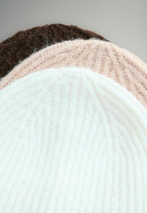 Drie gebreide mutsen gestapeld: donkerbruin, lichtroze en wit. Elk heeft een geribbelde textuur, die zachtheid en verschillende tinten benadrukt.