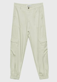 Pantalon cargo beige clair avec poignets élastiques, bouton sur le devant, fermeture éclair, poches latérales à rabat et poches avant inclinées, posé à plat sur un fond blanc.