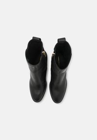 Bottines en cuir noir avec un design épuré, bout pointu, fermeture éclair sur le côté et tirette au talon, dotées d'une doublure intérieure douce.