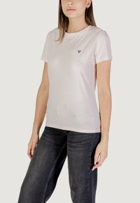 T-shirt rosa chiaro con maniche corte, scollatura rotonda e un piccolo logo triangolare sul petto. Tessuto morbido, design aderente e una leggera lucentezza.