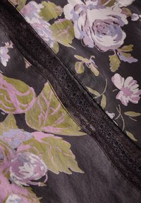 Gėlių audinys su didelėmis rausvomis ir violetinėmis rožėmis ant tamsios fono, su nėriniais apdaila ir tekstūruota paviršiumi.