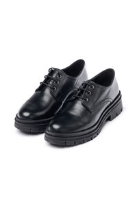Zapatos de cuero negro con puntera redondeada, cierre con cordones y suela de goma contrastante que presenta un patrón de textura en la banda de rodadura.